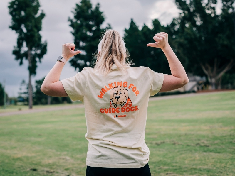 A woman wearing a PAWGUST t shirt stands with her back to the camera