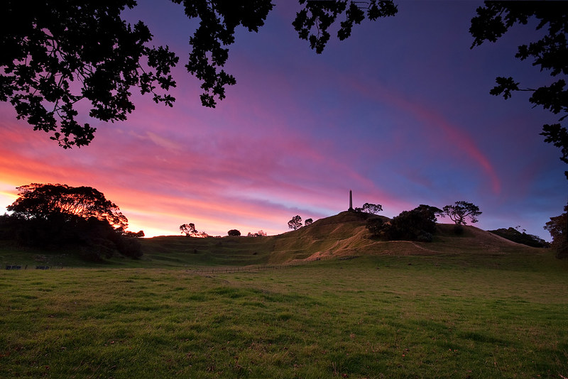 A view of One Tree Hill from Cornwall Park at sunset.